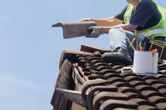 Residential roofing contractor replacing tiles on a sunny day at a home